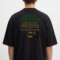 Camiseta com estampa frontal de "Stoic" no peito e estampa traseira com o texto "Love of One's Fate", acompanhada de parágrafo reflexivo e símbolos.