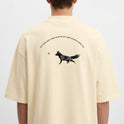 Camiseta com estampa frontal de símbolo geométrico com raposa centrada e texto abaixo e estampa traseira de raposa caminhando sob texto curvo e estrela.