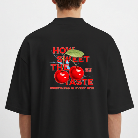 Camiseta com estampa traseira de cerejas reluzentes, folhas verdejantes e destaque para os dizeres "HOW SWEET THE TASTE" e "SWEETNESS IN EVERY BITE".