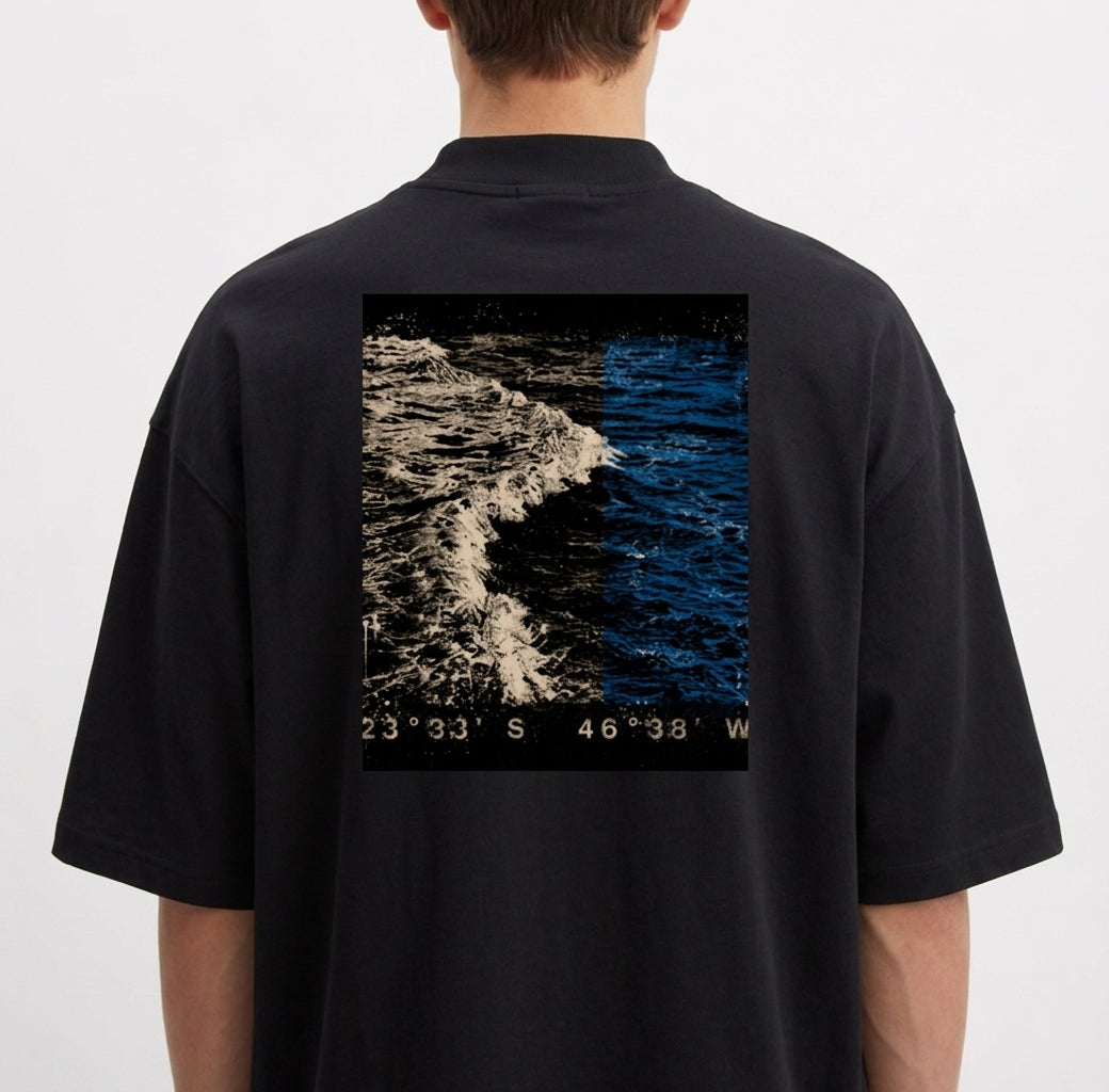 Camiseta com estampa frontal de símbolo minimalista em forma de flecha e estampa traseira de fotografia de oceano com coordenadas no rodapé.
