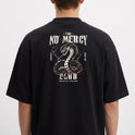 Camiseta com estampa frontal de texto estilizado "no mercy club" e estampa traseira de cobra detalhada, cercada por texto e símbolos impactantes.