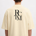 Camiseta com estampa frontal de lettering cursivo "Raceteam Built Different" e estampa traseira de iniciais sobrepostas em fonte de grande porte "RC TM".
