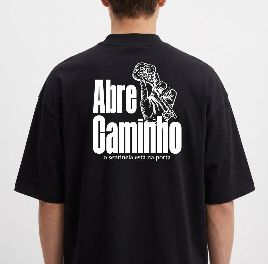 Camiseta com estampa frontal de chaves cruzadas e estampa traseira de mão segurando chave, junto com a frase "Abre Caminho o sentinela está na porta".