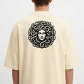 Camiseta com estampa frontal de logo estilizado "SERAVIA" e estampa traseira de figura mitológica com cabelos de serpentes emoldurada por elementos clássicos.