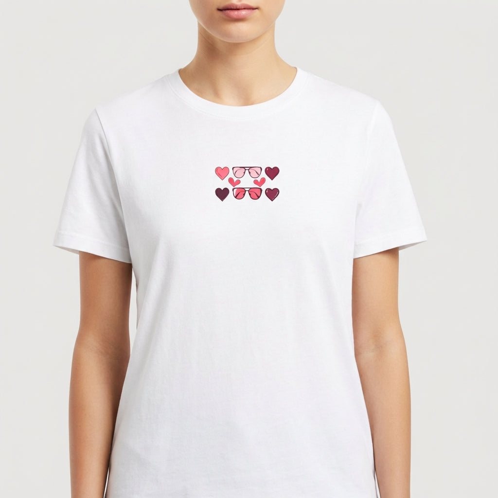 Camiseta com estampa frontal de óculos com lentes em formato de coração, cercados por pequenos corações em tons variados, criando um padrão charmoso.
