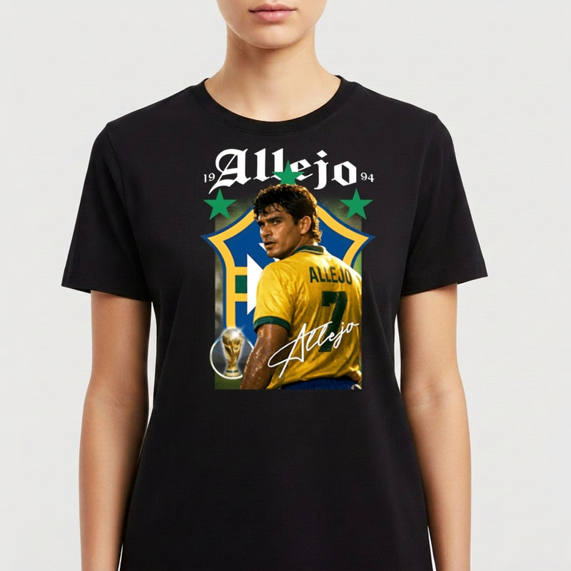Camiseta com estampa frontal de futebolista com uniforme, troféu e dois anos em destaque acima, em frente a um grande escudo estilizado, assinada em letra cursiva.