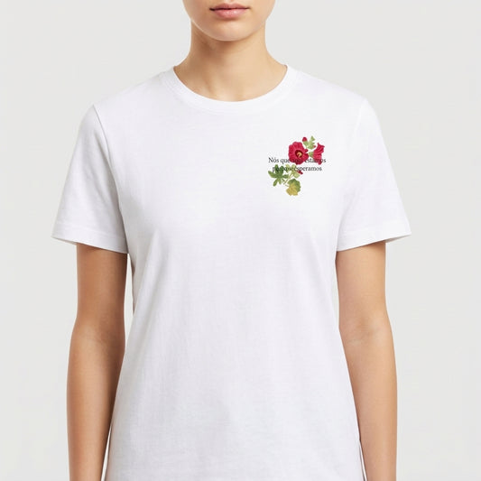 Camiseta com estampa frontal de flores delicadas acompanhadas da inscrição "Nós que aqui estamos".