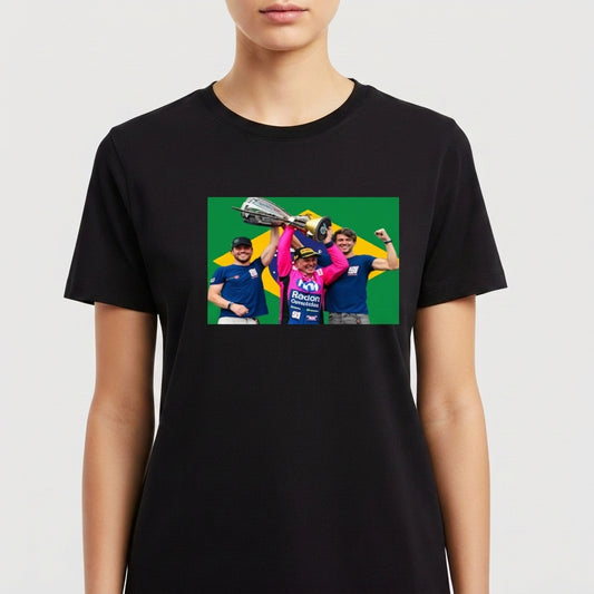 Camiseta com estampa frontal de três pessoas celebrando com um troféu acima de suas cabeças, em frente a uma bandeira estilizada ao fundo.