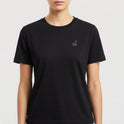 Camiseta com estampa frontal de uma pequena assinatura estilizada no peito e estampa traseira de uma foto em preto e branco de um jovem com faixa na cabeça e assinaturas.
