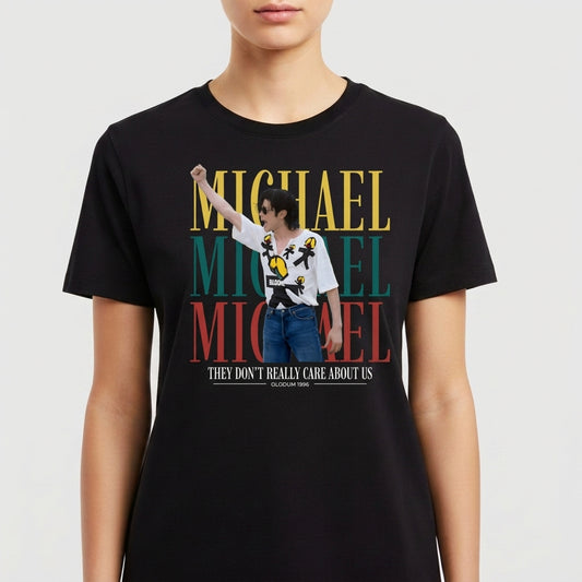Camiseta com estampa frontal de retrato de artista posando com óculos e camisa decorada, sobreposto ao nome repetido em blocos grandes, e frase adicional.