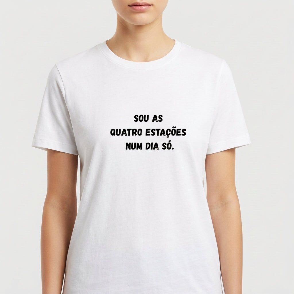 Camiseta com estampa frontal de frase estilizada: "Sou as quatro estações num dia só.", exibindo texto centralizado em letras destacadas.