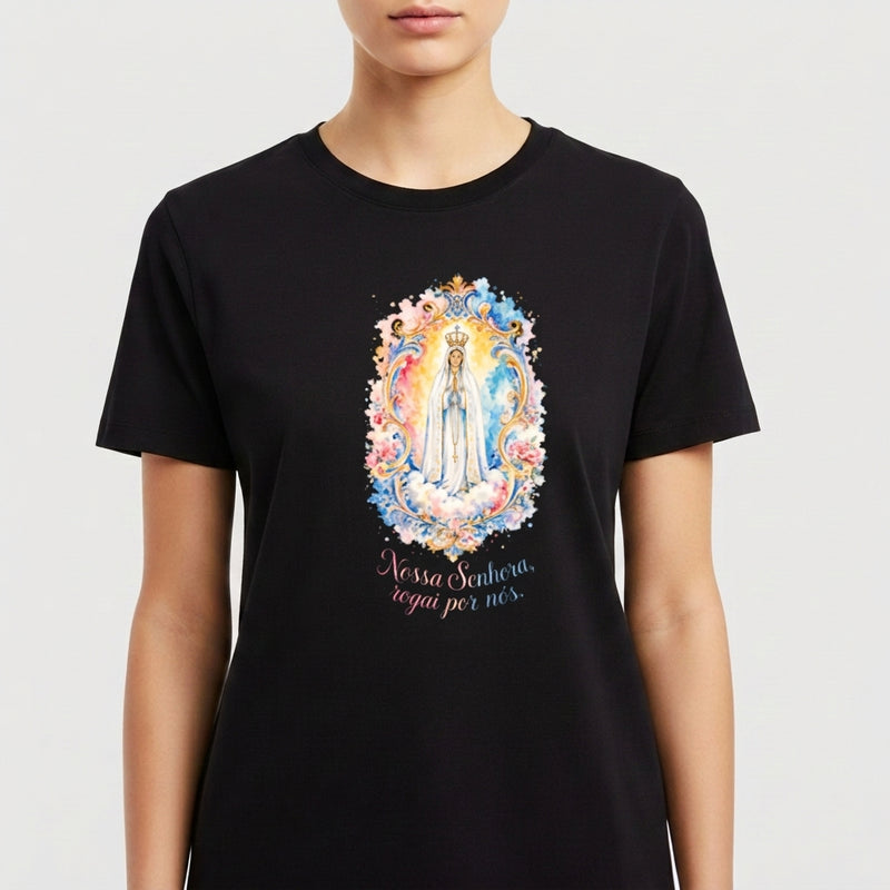 Camiseta com estampa frontal de figura religiosa emoldurada por detalhes florais e frase "Nossa Senhora, rogai por nós" e estampa traseira de logotipo estilizado "SV Santa Veste".