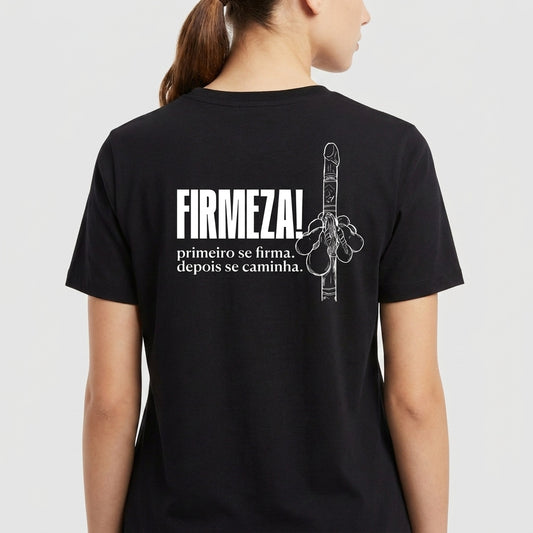 Camiseta com estampa traseira de mão fazendo gesto e com as palavras "FIRMEZA!" em destaque acima de frase inspiradora sobre firmeza e caminhada.