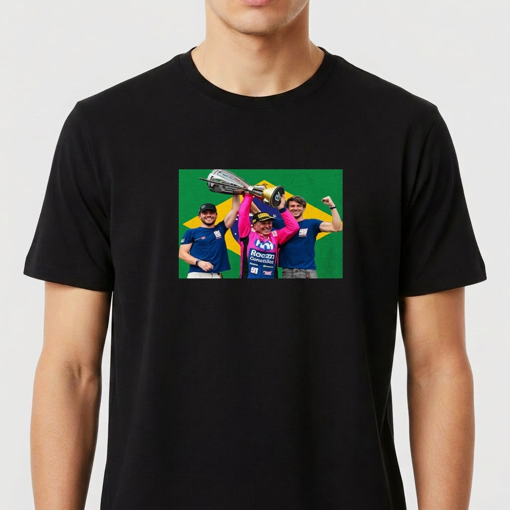 Camiseta com estampa frontal de três pessoas celebrando com um troféu acima de suas cabeças, em frente a uma bandeira estilizada ao fundo.