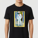 Camiseta com estampa frontal de homem de terno branco segurando bengala, chapéu elegante, ao fundo parede com graffiti e dois observadores.