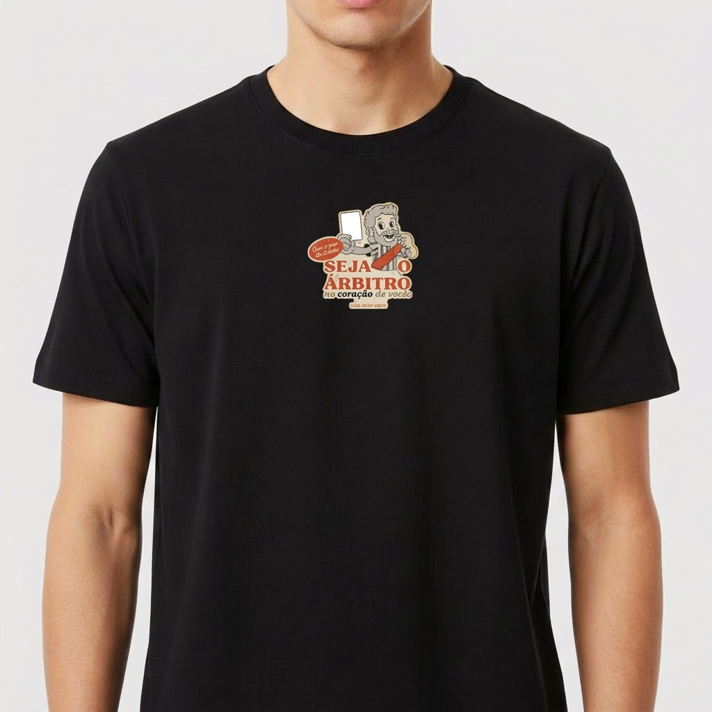 Camiseta com estampa frontal de personagem segurando um cartão vermelho e uma faixa com texto, ao lado de elementos que simbolizam arbitragem esportiva.