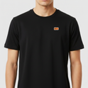 Camiseta com estampa frontal de um pequeno logotipo retangular e estampa traseira de um Papai Noel moderno segurando um rifle, rodeado por letras.