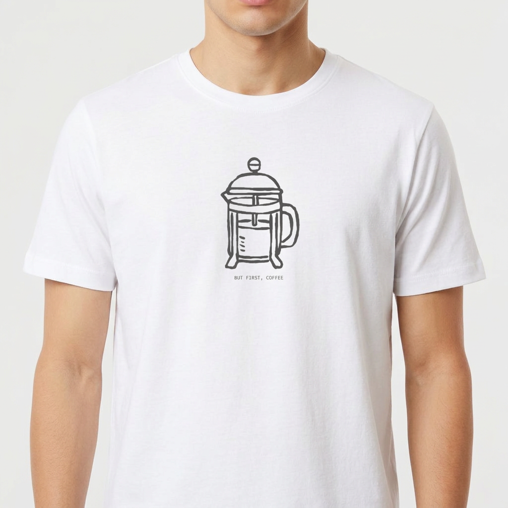 Camiseta com estampa frontal de cafeteira tipo prensa francesa desenhada de forma minimalista, acompanhada da frase "BUT FIRST, COFFEE" em letras discretas.