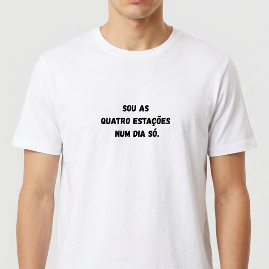 Camiseta com estampa frontal de frase estilizada: "Sou as quatro estações num dia só.", exibindo texto centralizado em letras destacadas.