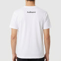 Camiseta com estampa frontal de texto estilizado "AUTISMO" colorido seguido de "Acal.mar.si" e frase pequena, e estampa traseira de "Acalmarsi".