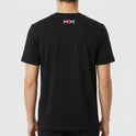Camiseta com estampa frontal de texto "Kuarup" acima de um símbolo geométrico preto e branco com detalhe central em vermelho, e estampa traseira de símbolo menor similar.