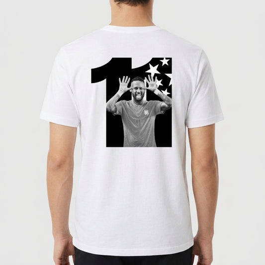 Camiseta com estampa traseira de número grande acompanhando imagem central de jogador de futebol em pose alegre, ladeado por estrelas estilizadas.