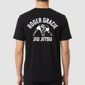 Camiseta com estampa frontal de logo e dois lutadores de jiu-jitsu em postura de combate, e estampa traseira de lutadores em ação sob logotipo em arco.