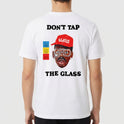 Camiseta com estampa frontal de martelo e texto "Don't Tap The Glass" e estampa traseira de rosto com boné, texto e blocos coloridos ao lado.