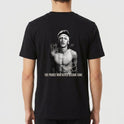 Camiseta com estampa frontal de uma pequena assinatura estilizada no peito e estampa traseira de uma foto em preto e branco de um jovem com faixa na cabeça e assinaturas.